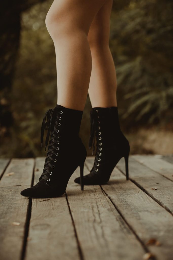 A woman wearing black lace up slim heel boots
